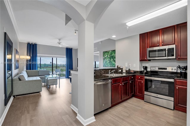 kitchen with ornamental molding, stainless steel appliances, ceiling fan, and light wood-type flooring