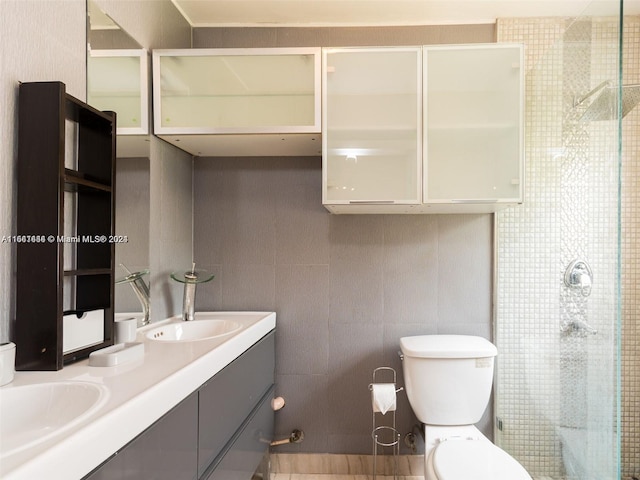 bathroom with walk in shower, vanity, toilet, and tile walls