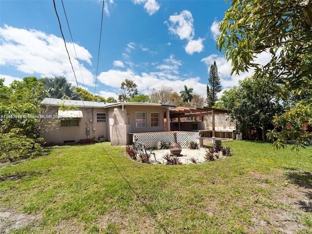 back of house featuring a pergola and a lawn