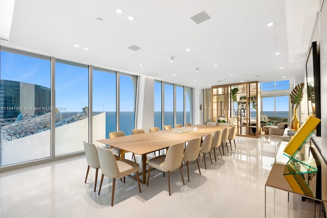 dining area featuring a water view, expansive windows, and light tile floors