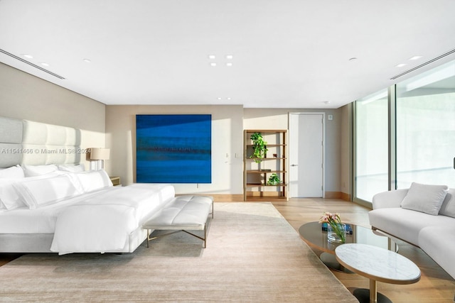 bedroom with floor to ceiling windows and light hardwood / wood-style flooring