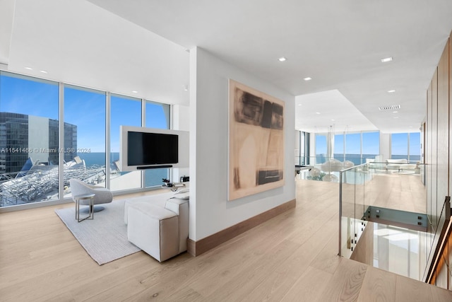 living room with a water view, floor to ceiling windows, and light wood-type flooring