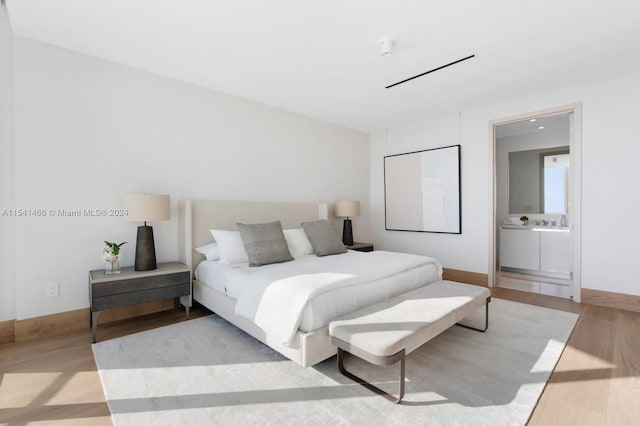 bedroom featuring connected bathroom and light hardwood / wood-style floors