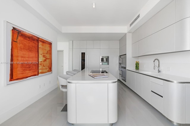 kitchen featuring tile walls, sink, light tile floors, stovetop, and white cabinetry