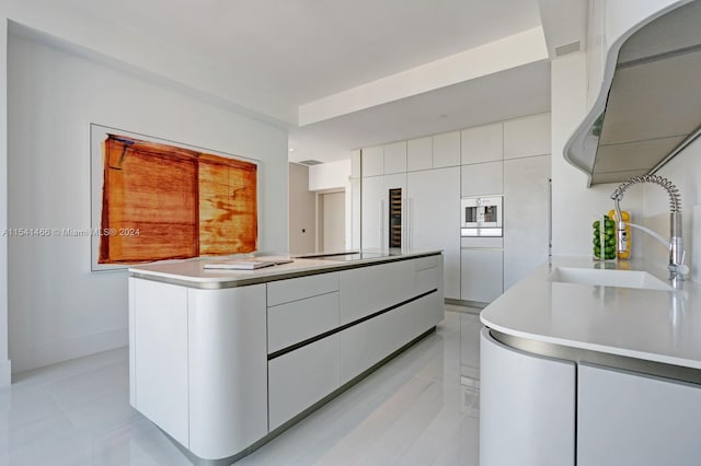 kitchen featuring light tile floors, black electric cooktop, white cabinetry, a kitchen island with sink, and sink