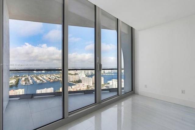 tiled empty room featuring floor to ceiling windows and a water view