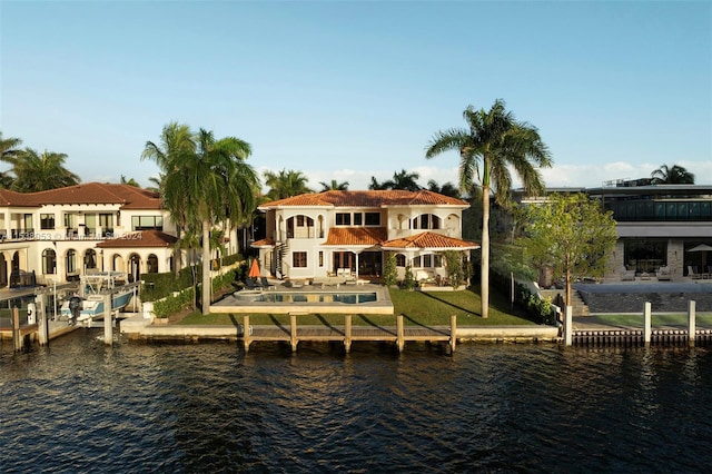 back of property with a yard, a water view, a patio area, and a balcony