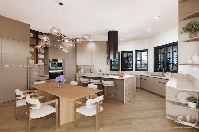 kitchen with sink, hanging light fixtures, light hardwood / wood-style flooring, decorative backsplash, and a breakfast bar area