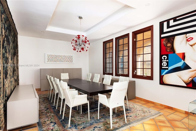 tiled dining room with a raised ceiling