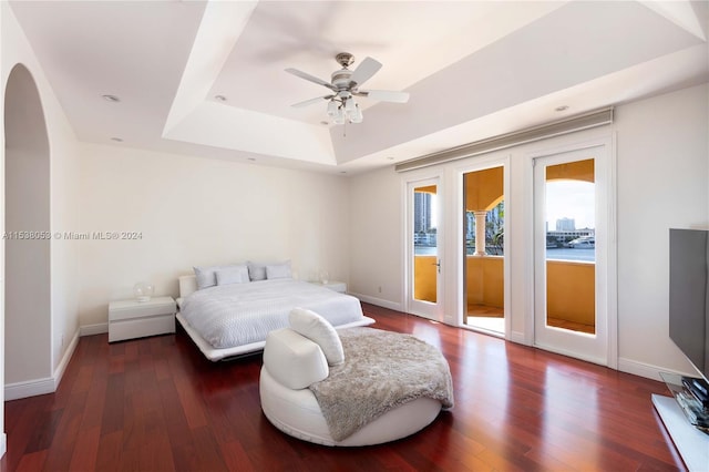 bedroom featuring access to exterior, dark hardwood / wood-style floors, a raised ceiling, and ceiling fan