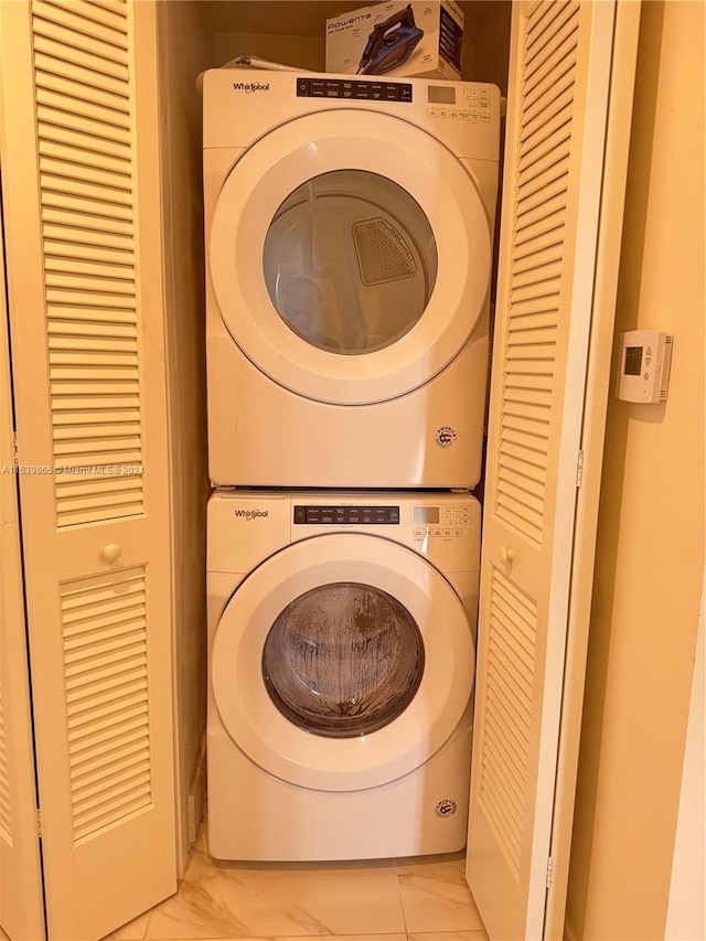 laundry area with stacked washer / dryer and light tile flooring