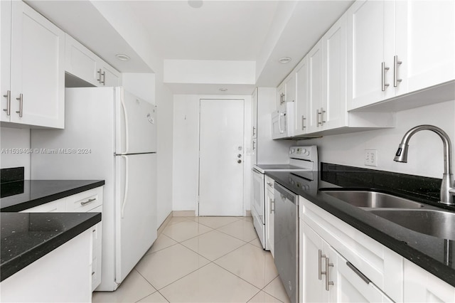 kitchen with white cabinets, light tile floors, sink, and dark stone counters