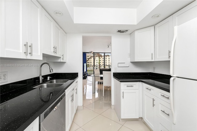 kitchen featuring light tile floors, dark stone counters, white refrigerator, stainless steel dishwasher, and white cabinetry