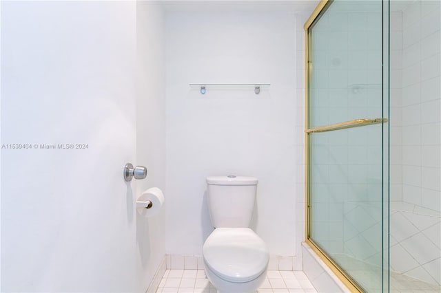 bathroom with toilet, a shower with door, and tile flooring