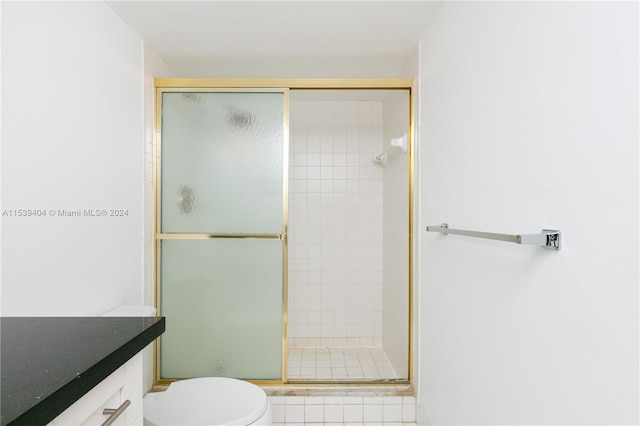 bathroom featuring toilet, vanity, and a shower with door