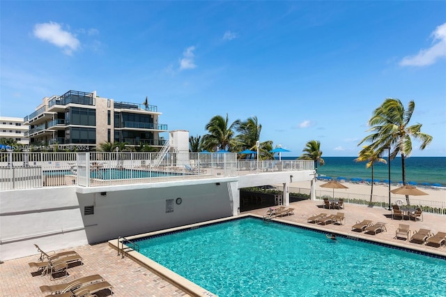 view of pool featuring a water view and a patio area