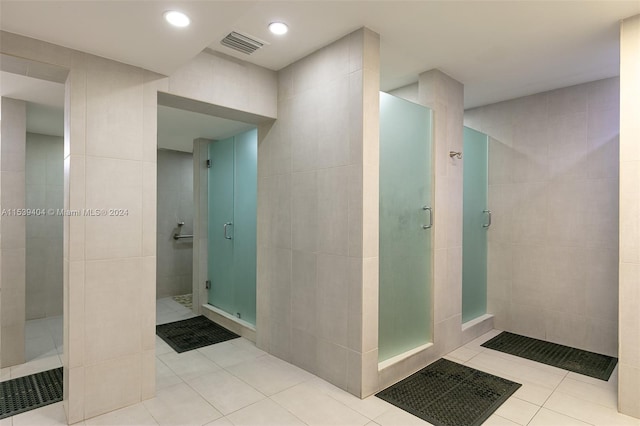 bathroom featuring tile flooring, a shower with shower door, and tile walls