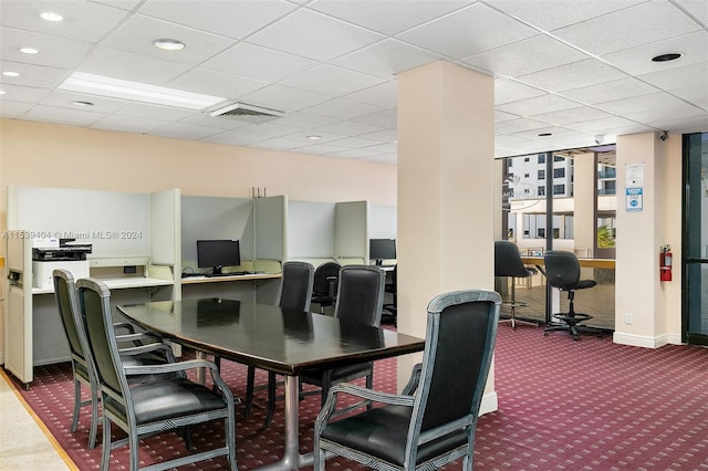 carpeted dining space with a drop ceiling