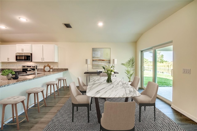 dining area featuring dark wood-type flooring and lofted ceiling