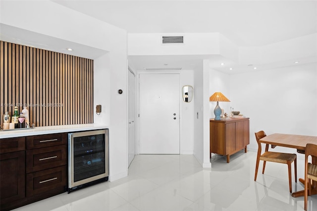 bar featuring dark brown cabinetry, light tile floors, and wine cooler