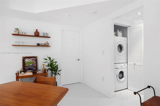 laundry room featuring stacked washer / drying machine and light tile floors