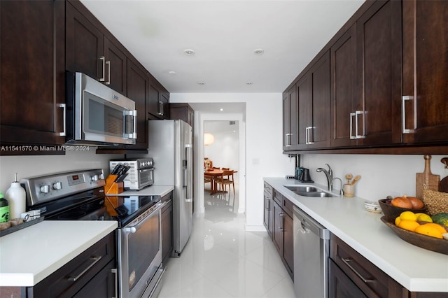 kitchen featuring dark brown cabinetry, stainless steel appliances, light tile floors, and sink