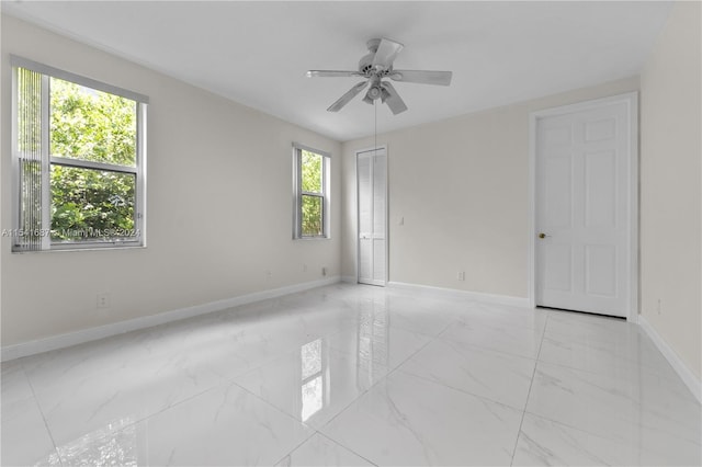 tiled spare room featuring ceiling fan and a healthy amount of sunlight