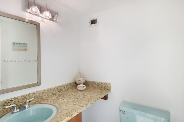 bathroom with toilet and vanity with extensive cabinet space