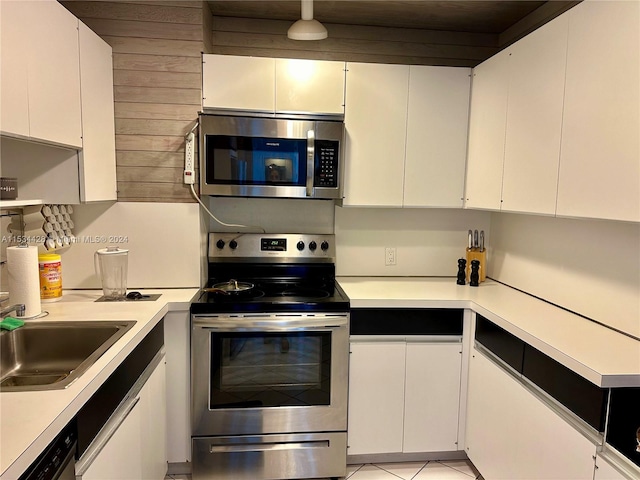 kitchen with sink, stainless steel appliances, light tile floors, and white cabinets