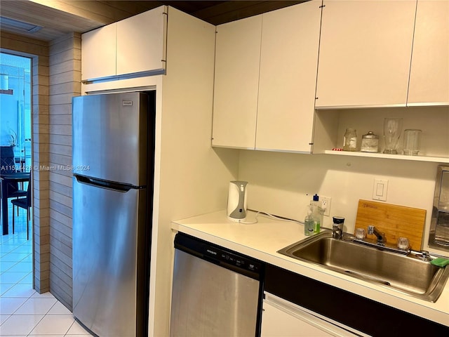 kitchen featuring stainless steel appliances, light tile floors, wooden ceiling, white cabinetry, and sink