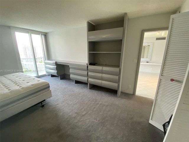 carpeted bedroom featuring a textured ceiling, ensuite bathroom, and access to outside