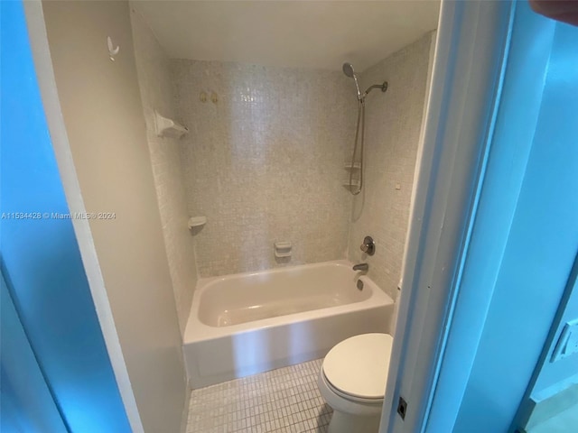 bathroom featuring toilet, tiled shower / bath, and tile flooring