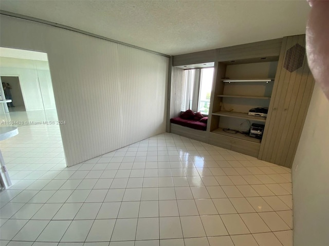 empty room with light tile floors and a textured ceiling