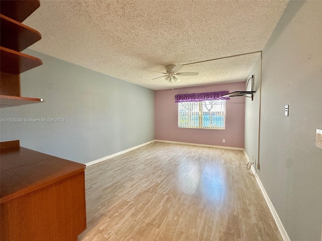 spare room with light wood-type flooring, ceiling fan, and a textured ceiling