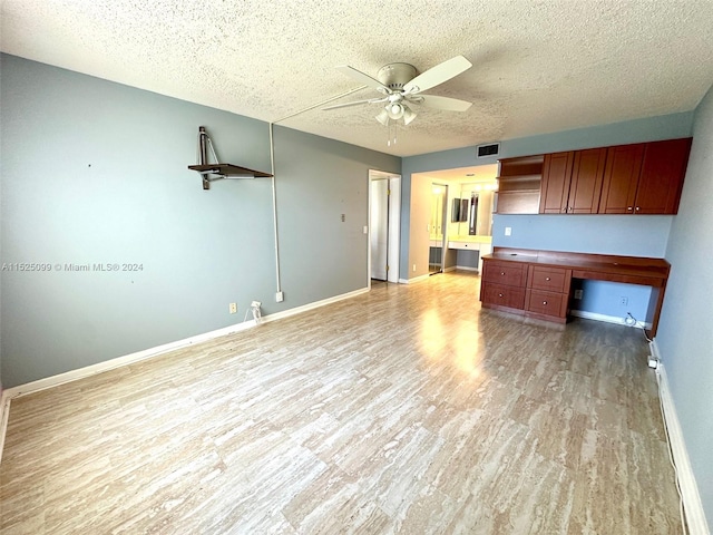 unfurnished living room featuring ceiling fan, a textured ceiling, and light wood-type flooring