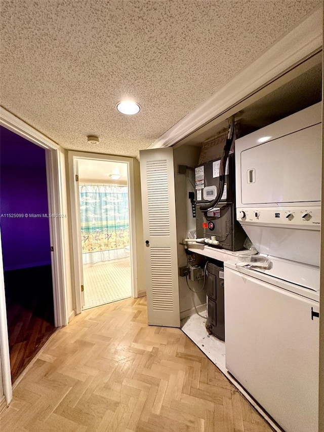 laundry area with stacked washer and clothes dryer, a textured ceiling, and light parquet floors