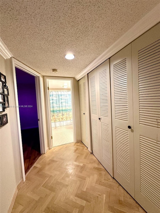 hallway with a textured ceiling and light parquet flooring