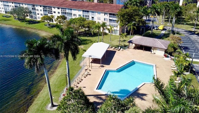 view of pool featuring a patio, a lawn, and a water view