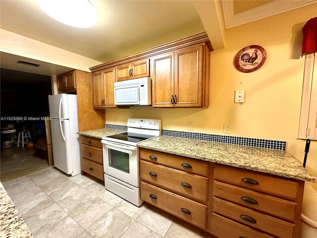 kitchen with light stone countertops, crown molding, white appliances, and light tile floors