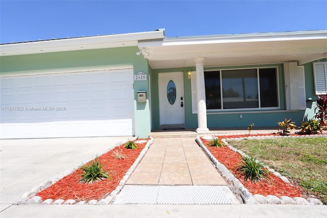 property entrance with driveway, stucco siding, and a garage