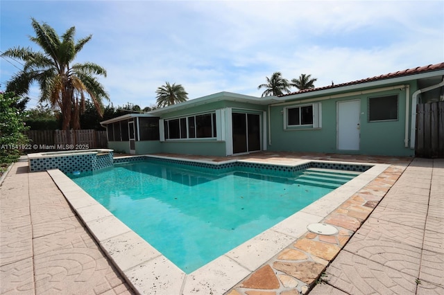 view of swimming pool with a sunroom, an in ground hot tub, and a patio