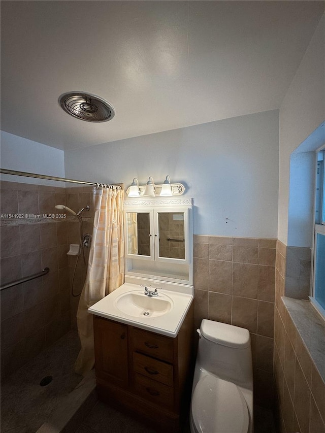 bathroom with a tile shower, toilet, vanity, and tile walls