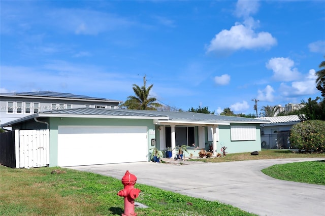 view of front of property with driveway, an attached garage, fence, a front lawn, and metal roof