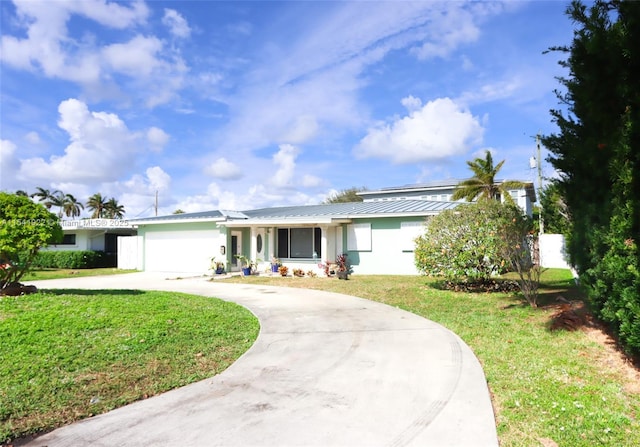 ranch-style home featuring a front yard, curved driveway, stucco siding, metal roof, and a garage
