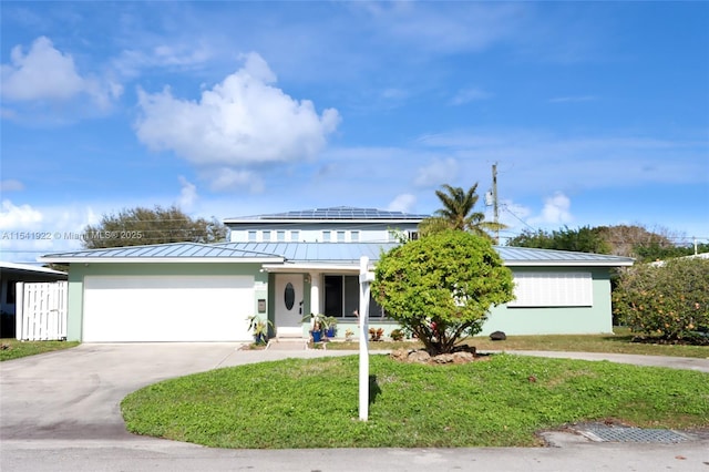 view of front facade featuring driveway, metal roof, a standing seam roof, and a garage