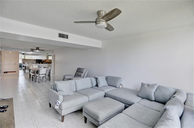 living room featuring light tile patterned floors, a textured ceiling, and ceiling fan