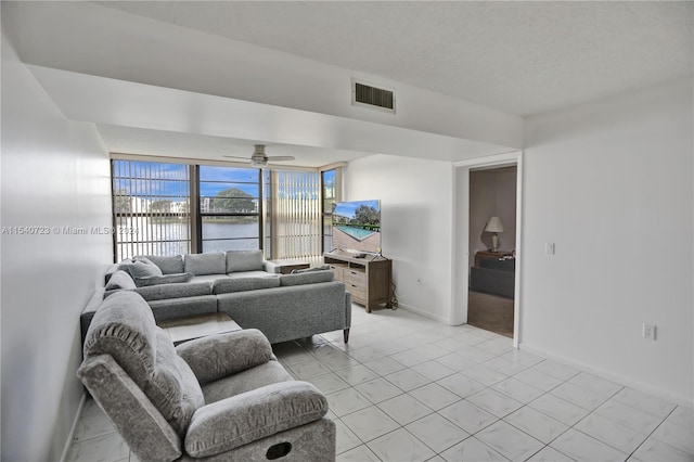 tiled living room featuring expansive windows, a water view, and ceiling fan