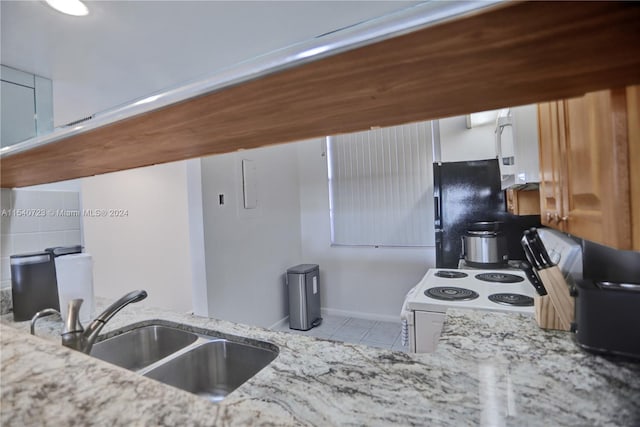 kitchen with white range with electric stovetop, white cabinets, sink, light stone counters, and light tile patterned floors