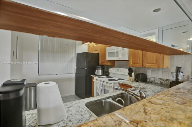 kitchen with tasteful backsplash, white appliances, sink, light tile patterned floors, and light stone countertops