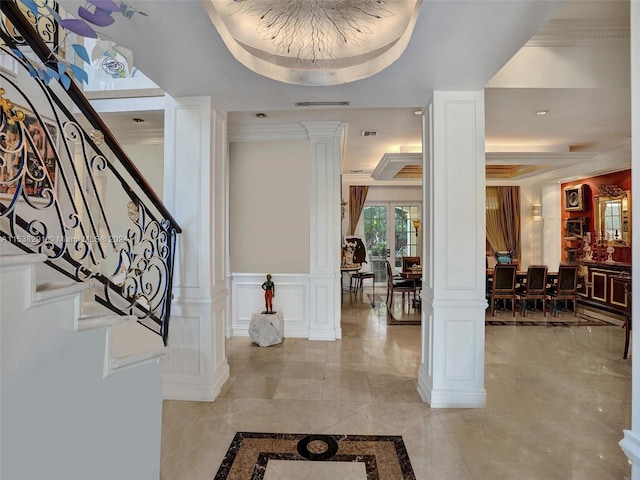 tiled entrance foyer with ornamental molding, decorative columns, and a tray ceiling